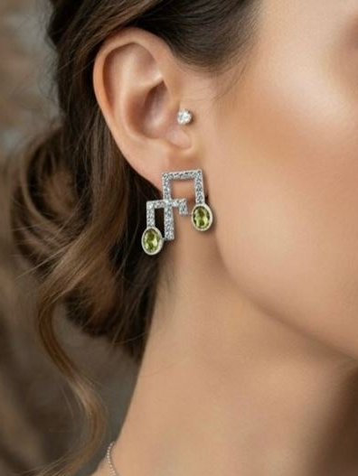 Close-up of a woman wearing diamond and peridot earrings with a blurred background