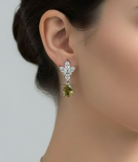 Close-up of a person wearing a star-shaped earring with a green gemstone on a neutral background